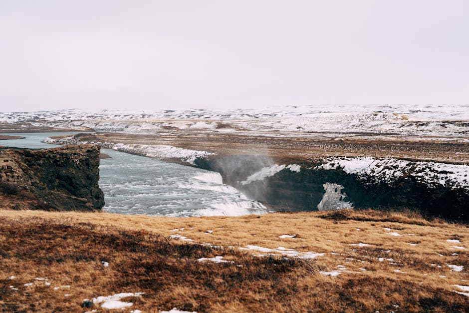 Impresionante vista de una cascada islandesa nevada rodeada de terreno accidentado.